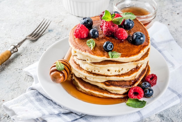 Gezond zomerontbijt, zelfgemaakte klassieke Amerikaanse pannenkoeken met verse bessen en honing