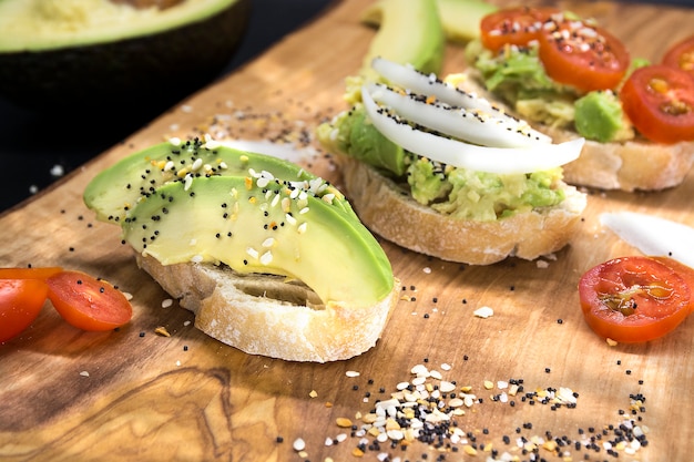 Gezonde avocado toast hapjes met zaden en tomaten op een houten bord wooden