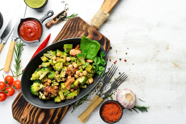 Gezonde avocadosalade, kikkererwten, broccoli en kip in een zwarte stenen plaat Bovenaanzicht Vrije ruimte voor uw tekst