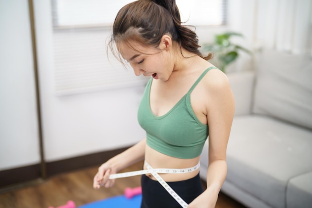 Gezonde Aziatische vrouw op dieet Gewichtsverlies Slimme vrouw meet de taille met meetband na dieet thuis gewichtsbeheersing
