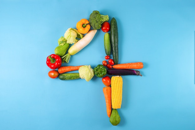 Gezonde biologische groenten gevormd in nummer vier 4 op blauwe achtergrond