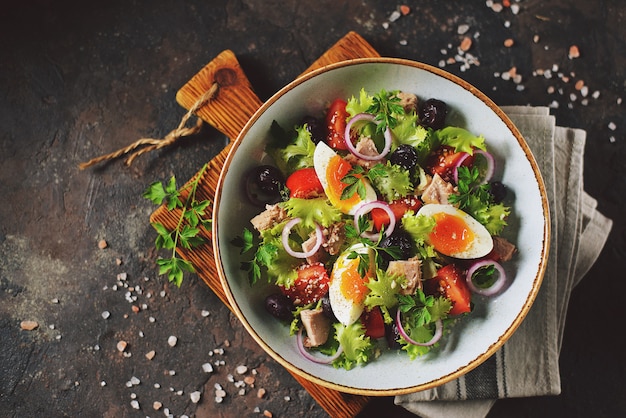 Gezonde biologische slasalade met tonijn uit blik, cherrytomaatjes, zongedroogde olijven, rode ui, ei en parmezaan