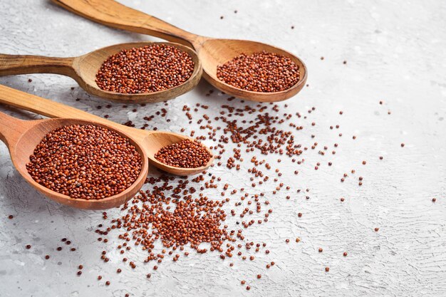 Gezonde biologische voeding Droge bruine quinoa in een houten lepel Op een grijze stenen achtergrond Bovenaanzicht