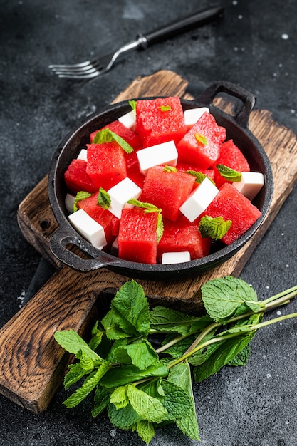 Gezonde biologische watermeloensalade met fetakaas. Zwarte achtergrond. Bovenaanzicht.