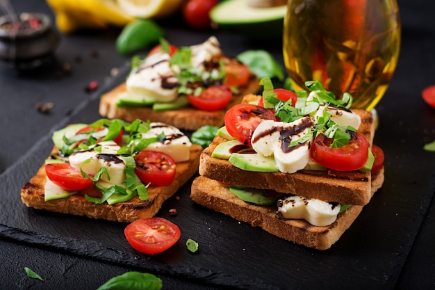 Gezonde broodjes met kaas, tomaten, avocado en basilicum