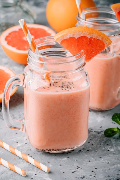 Gezonde detox-smoothie in metselaarkruik rode grapefruit met banaan en chiazaden op grijze achtergrond