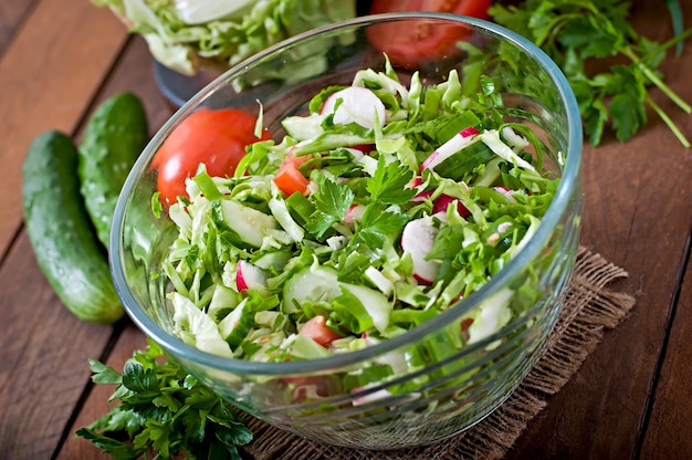 Gezonde dieetsalade van verse groenten in een glazen schaal op een houten achtergrond