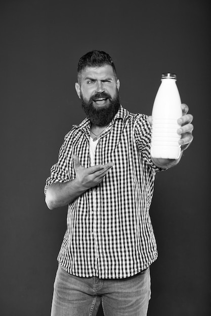 Gezonde drinkgewoonten Gelukkige hipster wijzend op fles voor het drinken van natuurlijke melk Bebaarde man presenteert drinkende zuivelproducten Consumptiemelk voor een betere spijsvertering