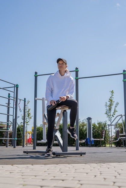 Gezonde en actieve levensstijl. Sport en fitness. Jonge sportieve vrouw in sporthandschoenen drinkwater uit thermosfles op sportveld