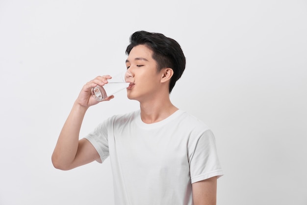 Gezonde en gelukkige jonge man die water drinkt terwijl hij thuis ontspant