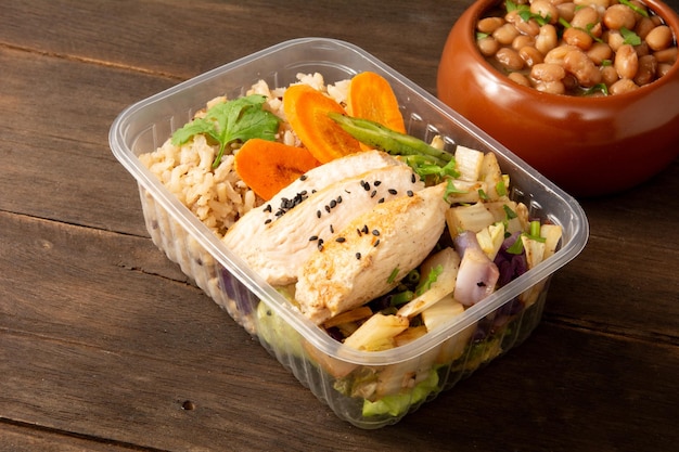 Gezonde fitness kip en rijst verpakt lunchbox maaltijd in houten achtergrond in de voorkant bovenaan