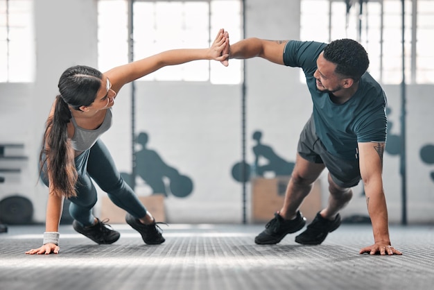 Gezonde fitte en actieve sportschoolpartners die samen trainen als een paar pushups en een high five doen Vriend en vriendin trainen en oefenen in een gezondheidsclub als onderdeel van hun trainingsroutine
