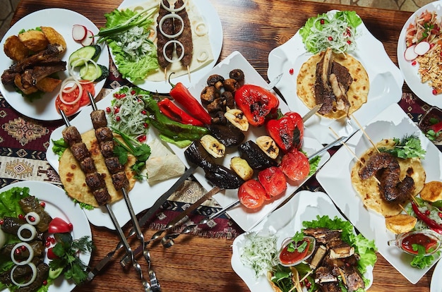 Gezonde gebarbecued magere kubieke varkensvlees kebabs geserveerd met een maïs tortilla en verse sla en tomaatsalade close-up view op een donkere achtergrond