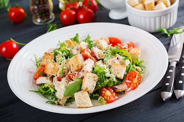 Gezonde gegrilde kip Caesarsalade met tomaten, kaas en croutons.