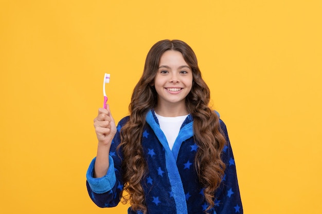 Gezonde glimlach. lachend kind doet ochtendroutine. tandheelkundige zorg met de beste tandpasta. jeugd geluk. vrolijke tiener die tanden gaat poetsen. kind in nachtkleding met tandenborstel.