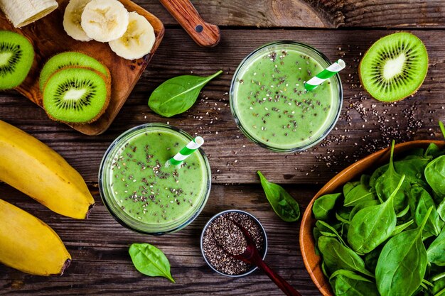 Gezonde groene smoothie met banaan-kiwi-spinazie en chiazaden in glazen potten op een rustieke achtergrond