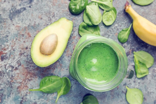 Gezonde groene smoothie met spinazie, avocado-banaan en chiazaden op grijze steen