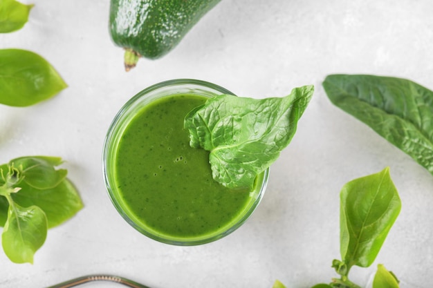 Gezonde groene smoothie met spinazie, avocado, banaan en veganistische melk in glas en verse ingrediënten bovenaan