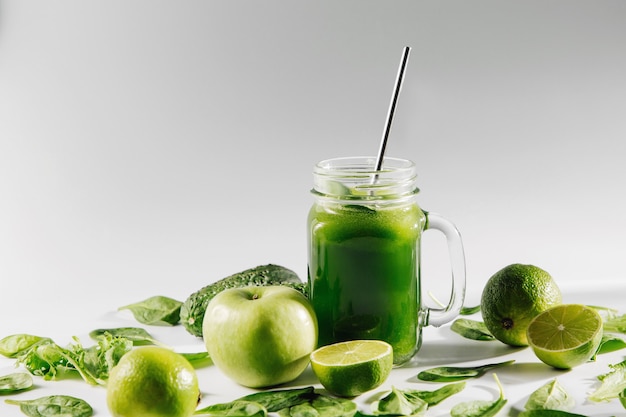 Gezonde groene smoothie met spinazie en groene groenten en fruit op witte tafel