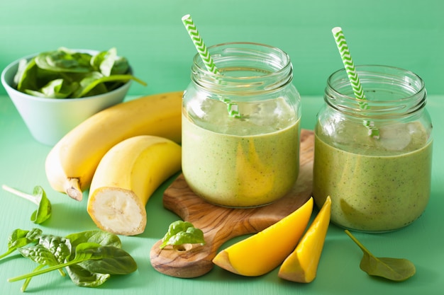 Gezonde groene smoothie met spinazie mangobanaan in glazen potten