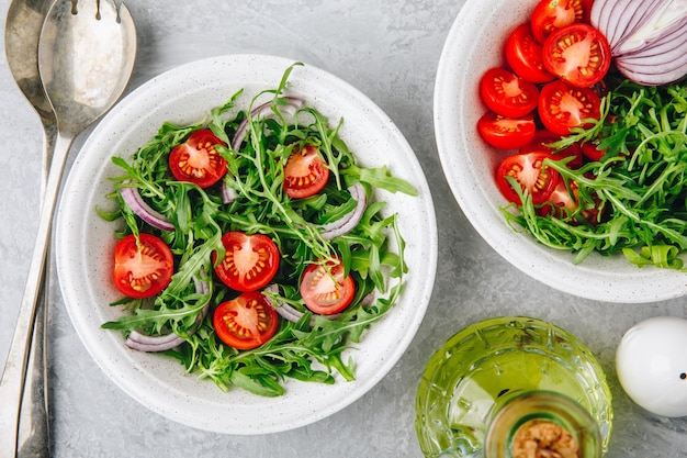 Gezonde groene verse rucola slakom met tomaten en rode uien Uitzicht van bovenaf