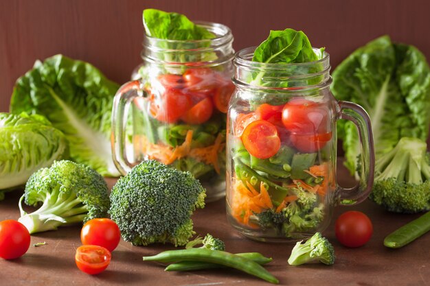 Gezonde groentesalade in metselaarkruik. tomaat broccoli wortel erwt