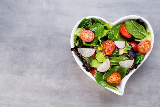 Gezonde groentesalade van verse tomaten, spinazie, sla en radijs.