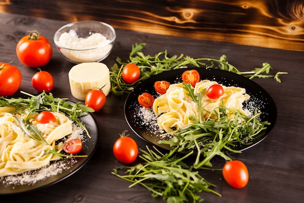 Gezonde heerlijke pasta naast tomaten, groen en Parmezaanse kaas op houten achtergrond