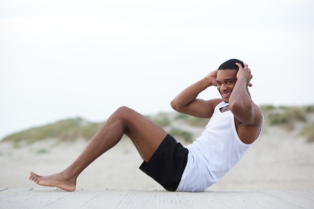 Gezonde jonge man doen zit ups op het strand