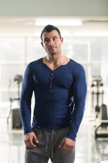 Gezonde jonge man in blauwe tshirt staande sterke en flexibele spieren gespierde atletische bodybuilder Fitness Model poseren na oefeningen