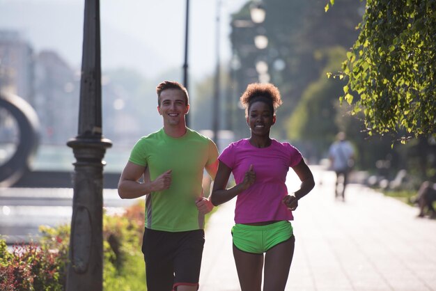 gezonde jonge multi-etnische paar joggen in de stad in de vroege ochtend met zonsopgang op de achtergrond