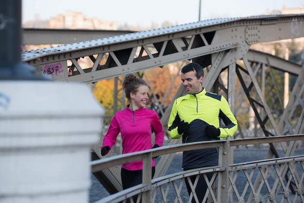 gezonde jonge paar joggen in de stad in de vroege ochtend met zonsopgang op de achtergrond