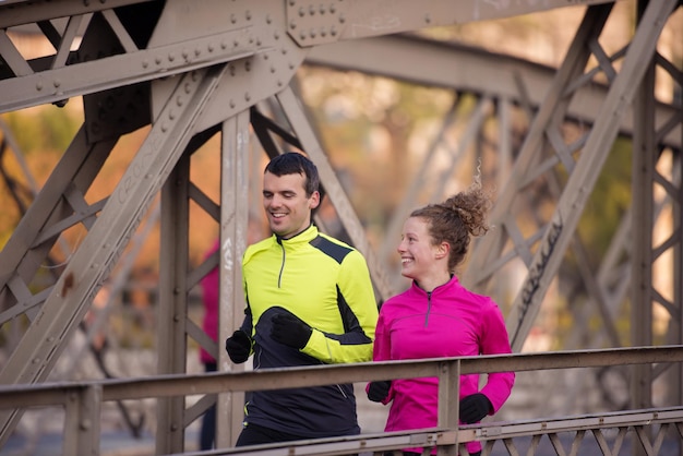 gezonde jonge paar joggen in de stad in de vroege ochtend met zonsopgang op de achtergrond