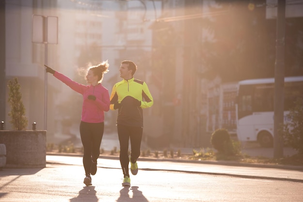 gezonde jonge paar joggen in de stad in de vroege ochtend met zonsopgang op de achtergrond