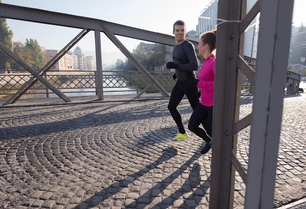 gezonde jonge paar joggen in de stad in de vroege ochtend met zonsopgang op de achtergrond