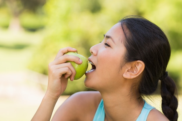 Gezonde jonge vrouw die appel in park eet