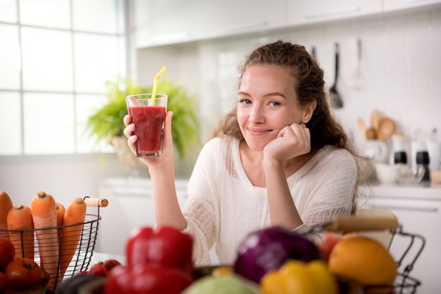 Gezonde jonge vrouw in een keuken met fruit en groenten en sap