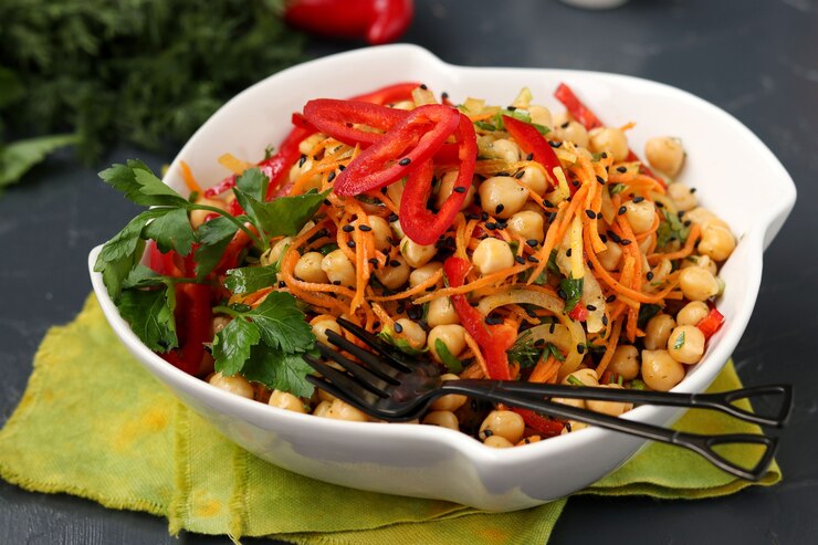 Foto gezonde kikkererwten, koreaanse wortel, paprika en uiensalade versierd met zwarte sesam
