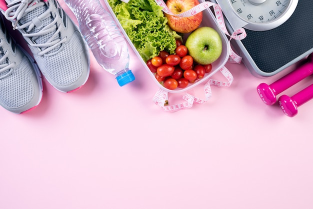 Gezonde levensstijl, eten en sport op roze pastel achtergrond.