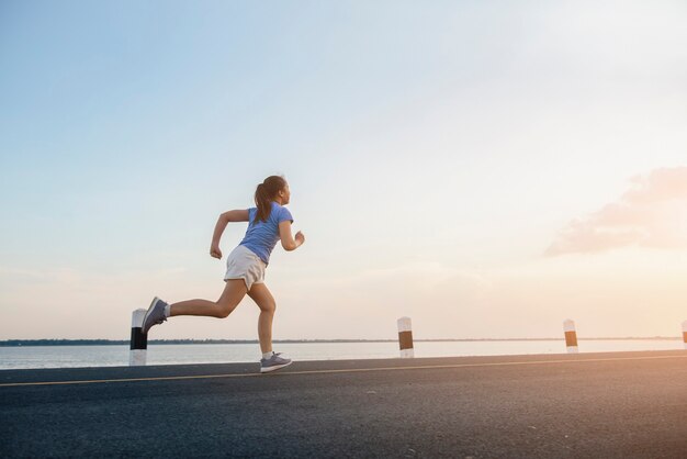 Gezonde levensstijl jonge fitness vrouw die aan de rivier loopt.