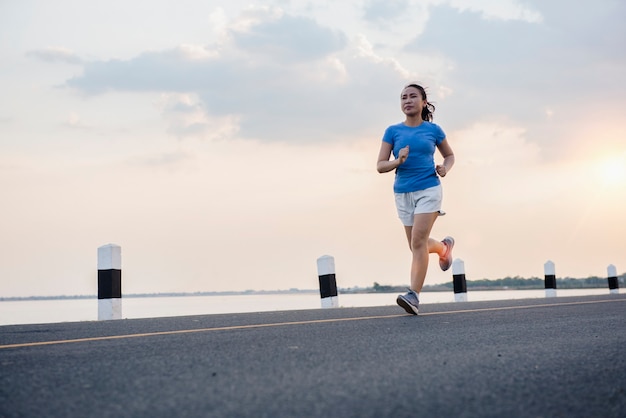 Foto gezonde levensstijl jonge fitness vrouw die aan de rivier loopt.