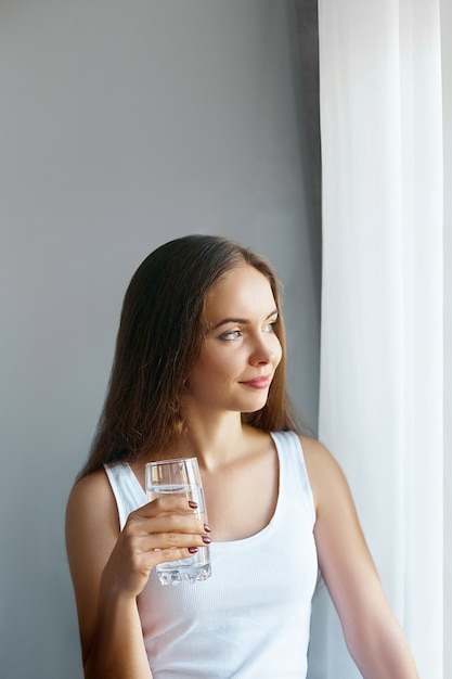 Gezonde levensstijl. jonge vrouw drinken uit een glas vers water