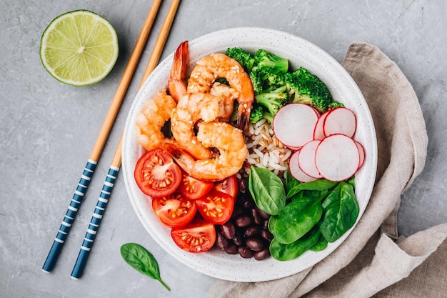 Gezonde lunch Garnalen Burrito Bowl met bruine rijst spinazie radijs zwarte bonen tomaat en broccoli