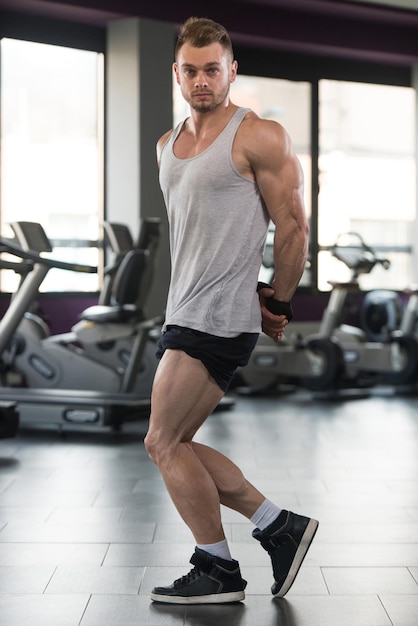 Gezonde Man In hemd permanent sterk op sportschool en buigen spieren gespierde atletische Bodybuilder Fitness Model poseren na oefeningen