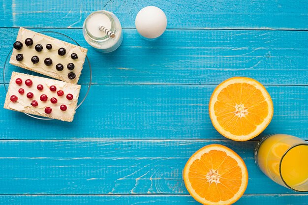 Gezonde ontbijt zoete broodjes met roomkaas en verse bessen en fruit op blauwe achtergrond