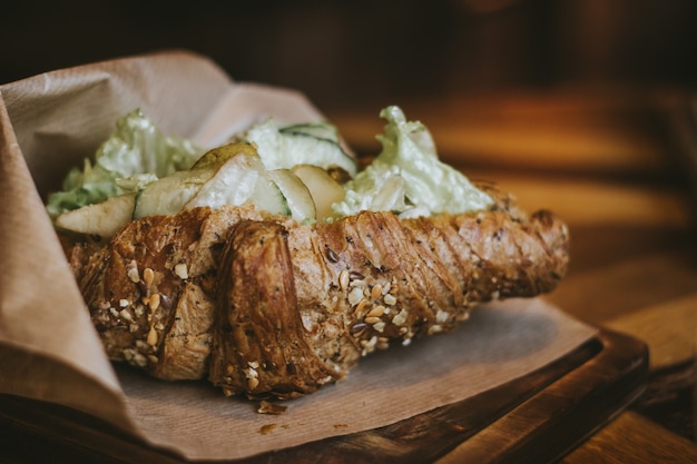 Gezonde ontbijtcroissant met sesamsalade, komkommer en peer op een houten tafel