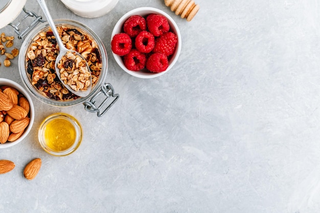 Gezonde ontbijtgranola met verse frambozenamandel en honing op grijze steen als achtergrond bovenaanzicht