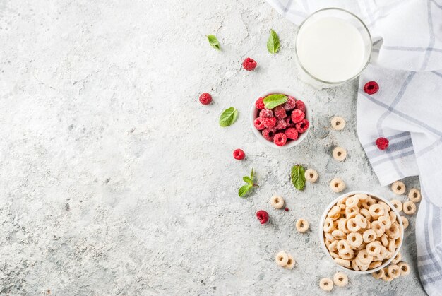 Gezonde ontbijtingrediënten. Ontbijtgraan maisringen, melk of yoghurtglas, frambozen en munt