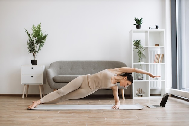 Gezonde oudere vrouw die thuis moderne yoga beoefent met Vasisthasana-oefening