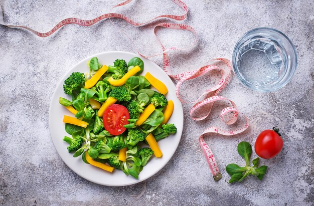 Gezonde plantaardige salade, water en meetlint